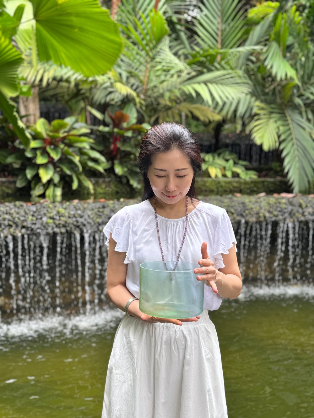 Michele, founder of Soulsound Asia, holding a sound bowl in a garden